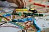 Färgade spelpjäser i form av tågvagnar på en karta, med en hand i bakgrunden.