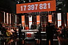 TV-studio med publik, programledare och stor digital insamlingssiffra ovanför scenen.