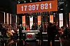 TV-studio med publik, programledare och stor digital insamlingssiffra ovanför scenen.