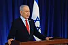 Benjamin Netanyahu vid en talarstol under en presskonferens i Jerusalem, med israelisk flagga bakom.