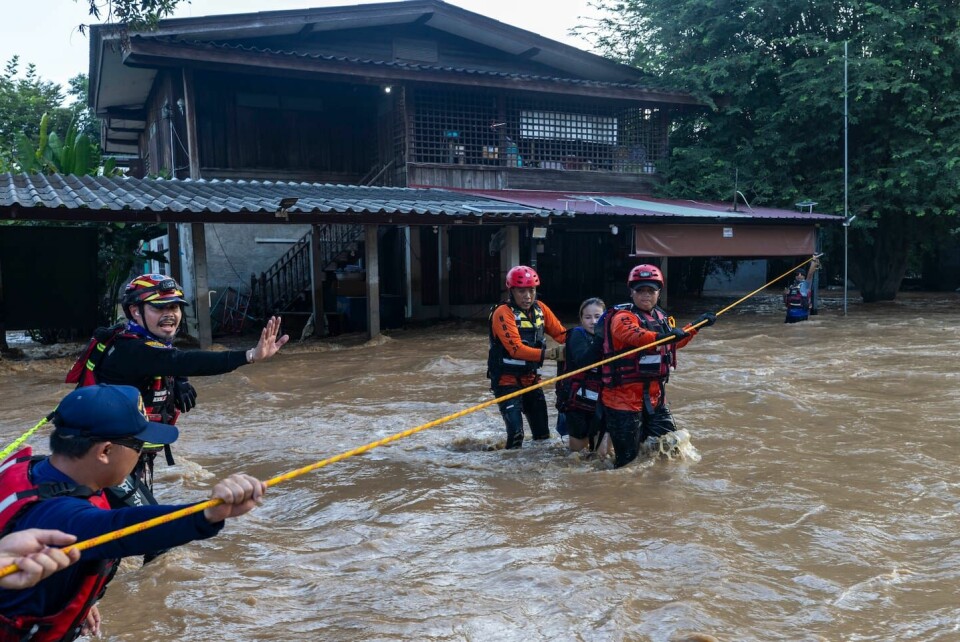 Räddningsarbetare hjälper en kvinna undan en översvämmad gata i Chiang Mai i norra Thailand.