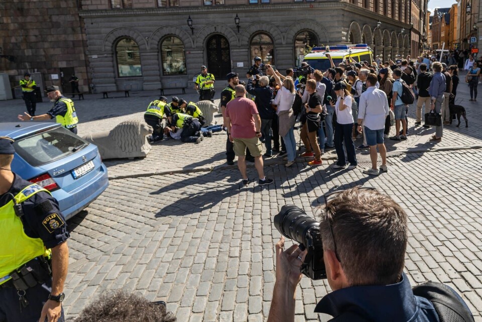 Polisen brottar ned en man som försöker ta sig fram till koranbrännarna. Två män bränner koranen på Mynttorget i centrala Stockholm.