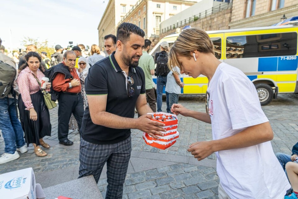 Muslimer delar ut kakor som ett fredligt sätt att protestera mot koranbränningarna. Två män bränner koranen på Mynttorget i centrala Stockholm.