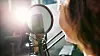 Shot of a woman speaking into a microphone in a recording studio